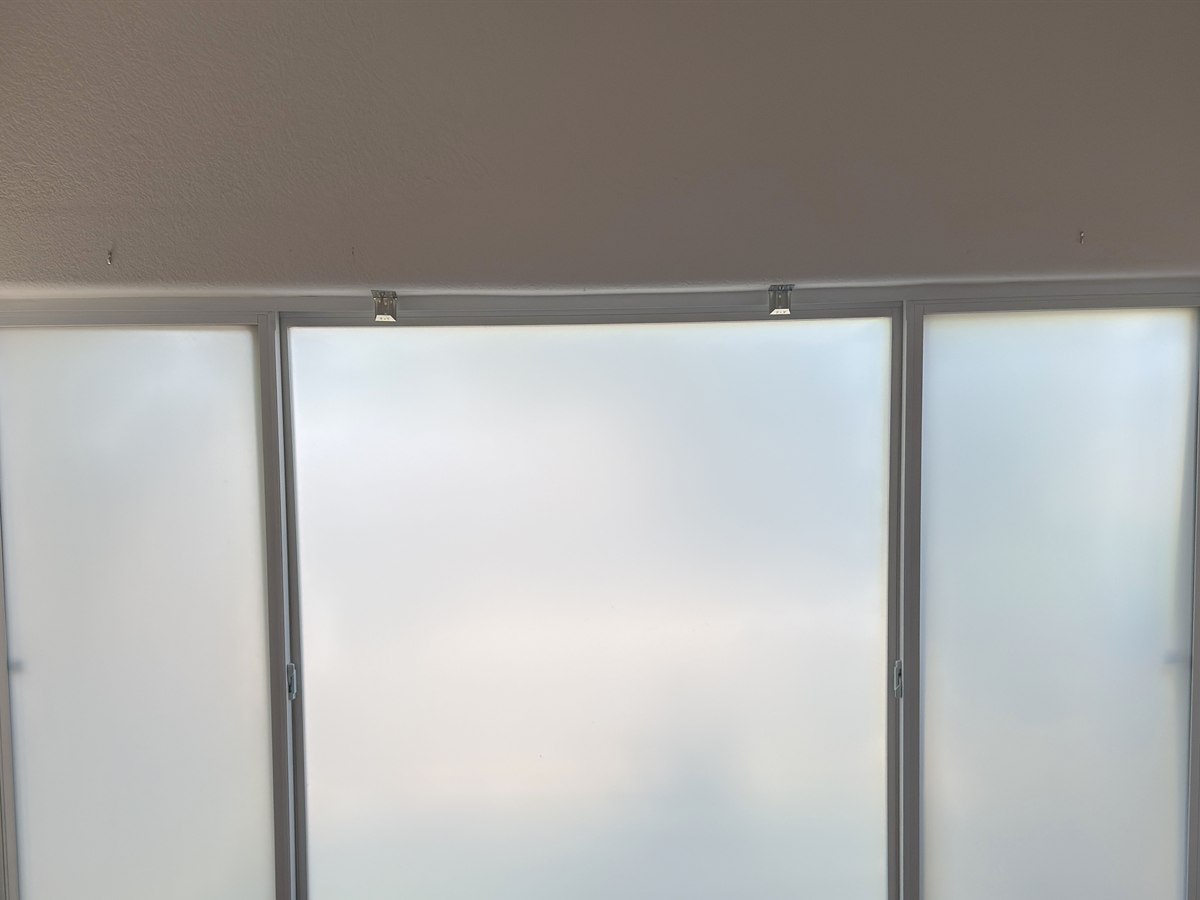 A three-pane window covered in frosted privacy film